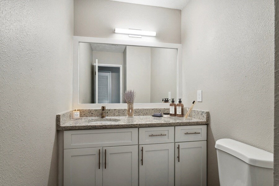 Model apartment bathroom with a sink and a mirror and a toilet