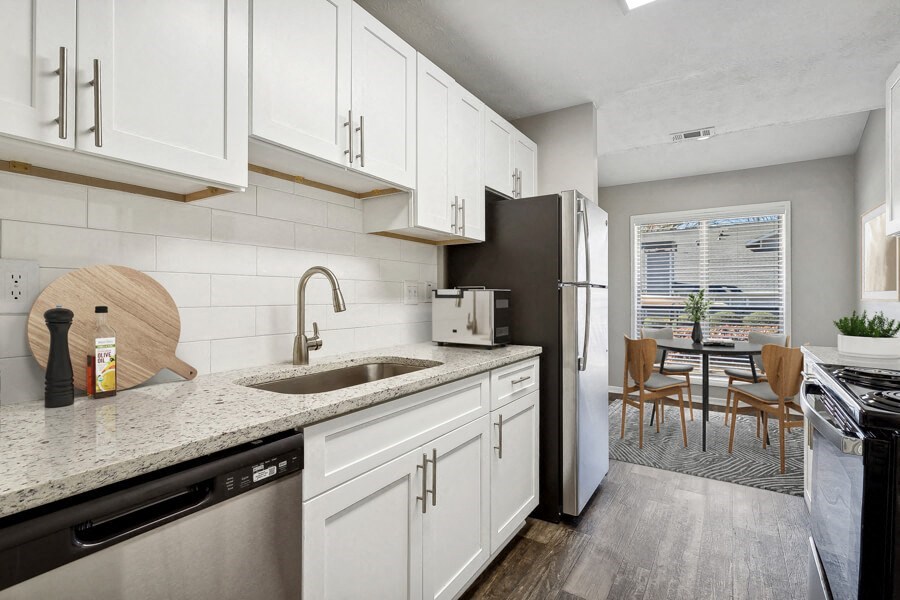 Model apartment kitchen with white cabinets and a sink and a refrigerator