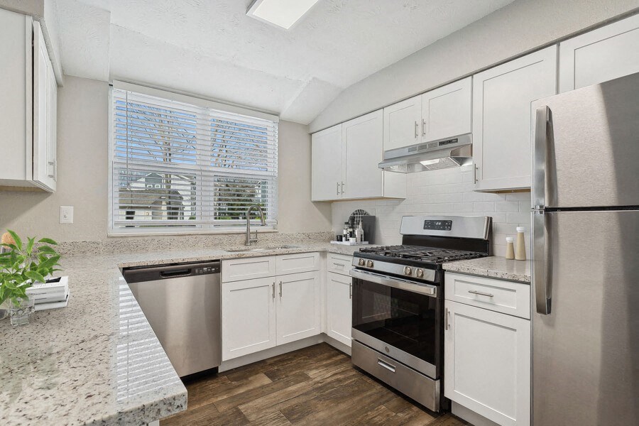 Model apartment kitchen with white cabinets and stainless steel appliances