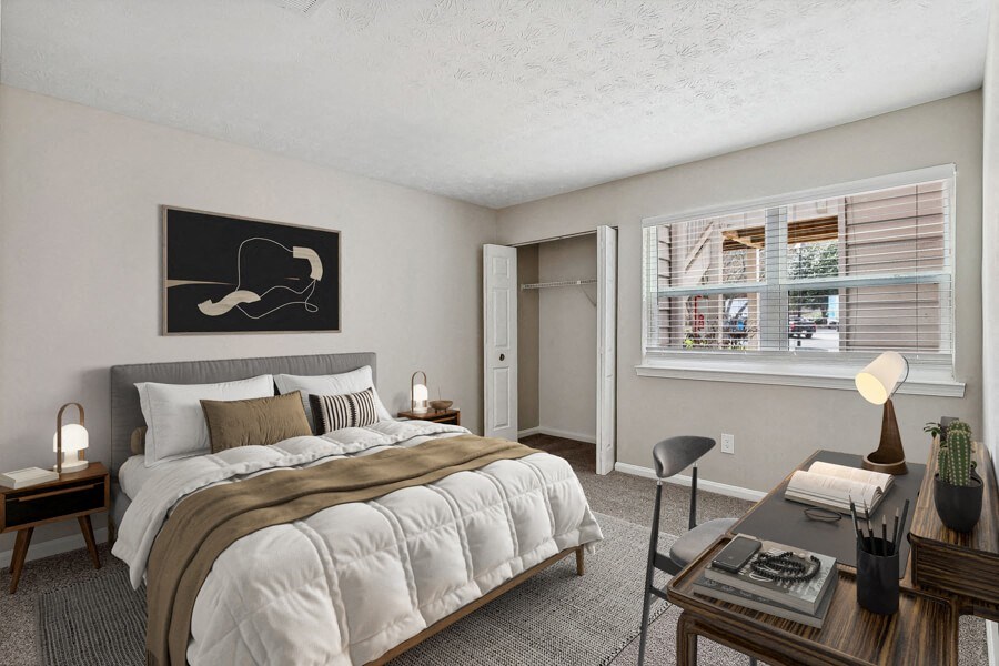 Model apartment bedroom with a bed and a desk and a window