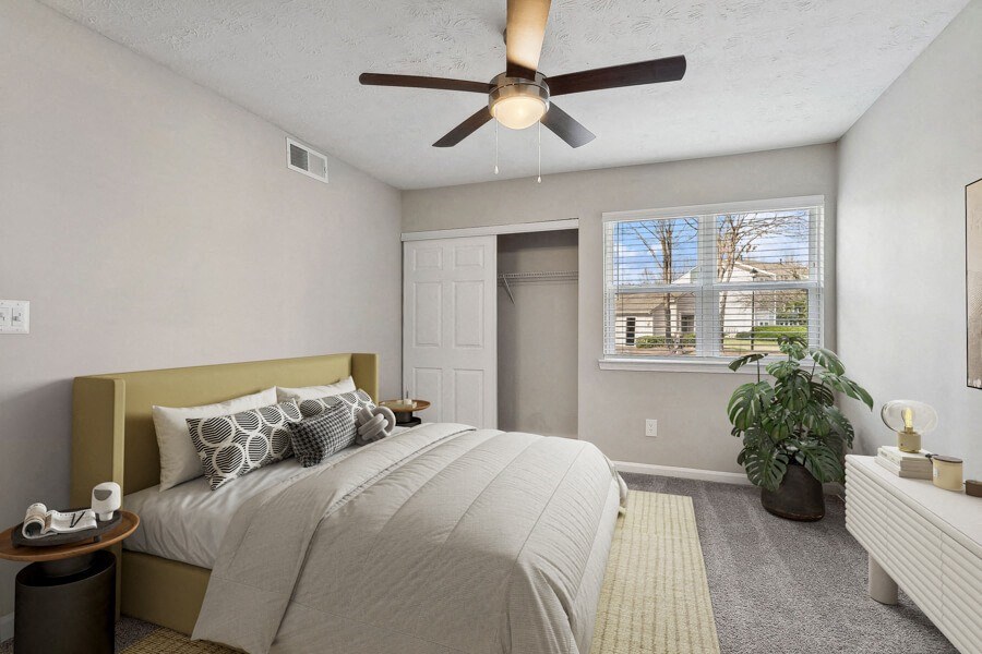Model apartment bedroom with a bed and a ceiling fan