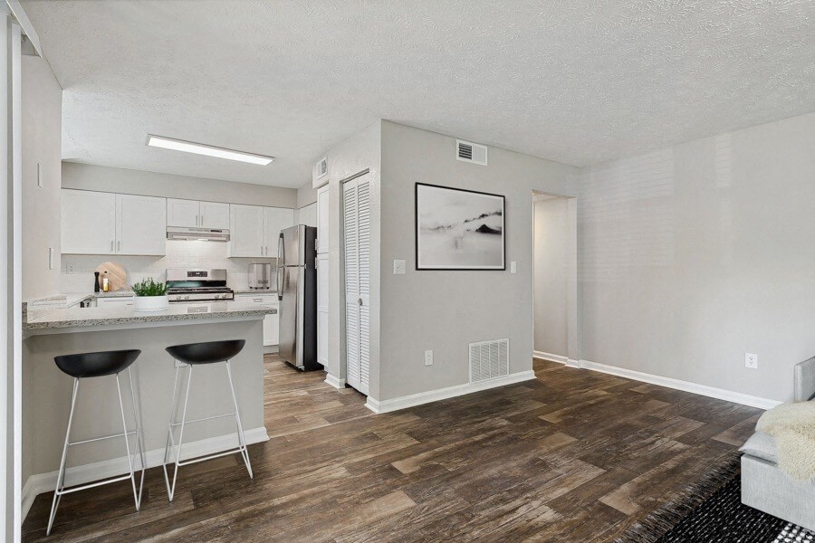 Model apartment kitchen and living room with a bar and stools