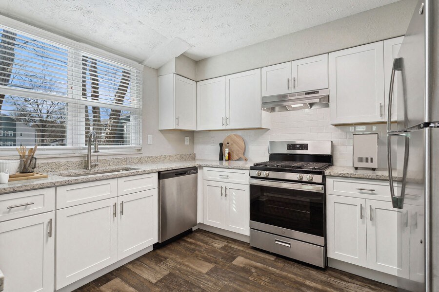 Model apartment kitchen with white cabinets and stainless steel appliances