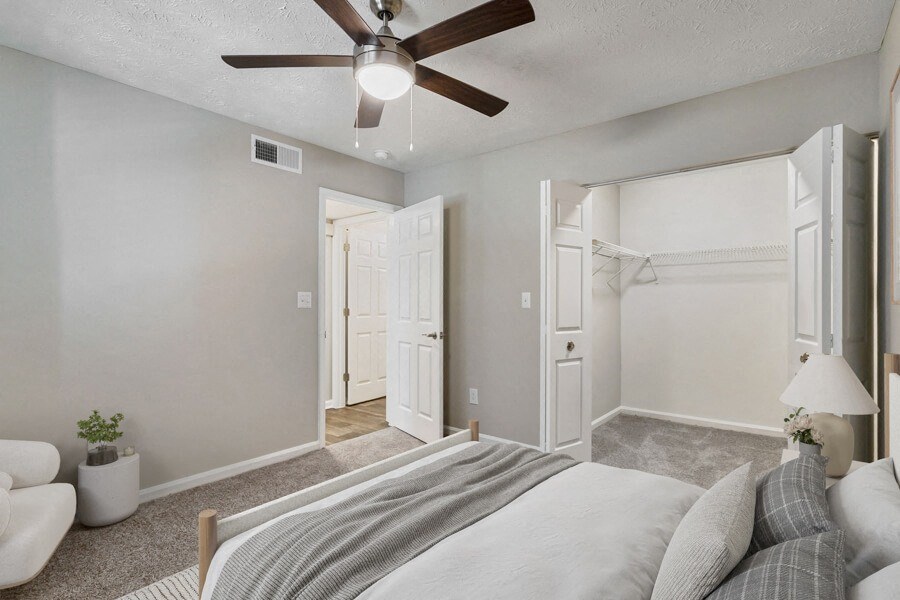 Model apartment bedroom with a bed and a ceiling fan