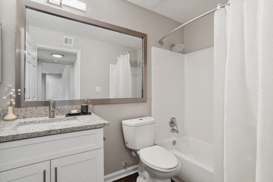 Model apartment bathroom with a sink toilet and a mirror
