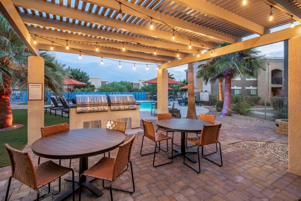 Outdoor lounge area with grill and pool in the background