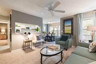 a living room with a ceiling fan and a coffee table in the middle of the room