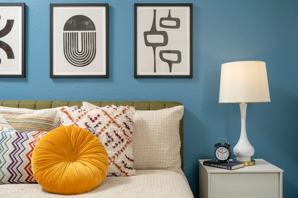 a bedroom with a blue wall and three pieces of art above the bed