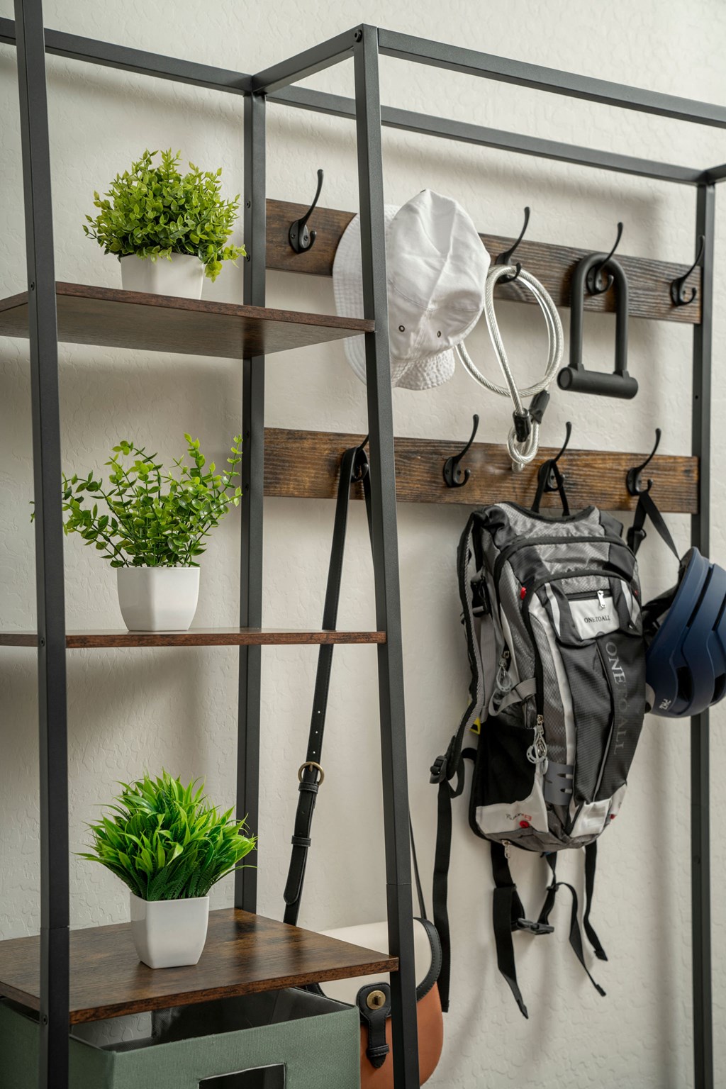 a metal shelving unit with hooks and a backpack on it and plants on the shelves