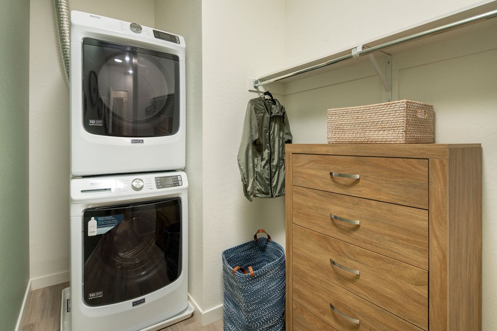 a washer and dryer sit next to a dresser in a laundry room