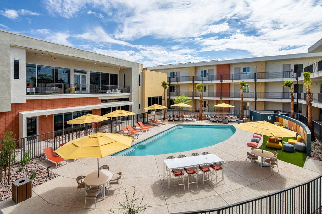 a swimming pool with yellow umbrellas and red and white chairs