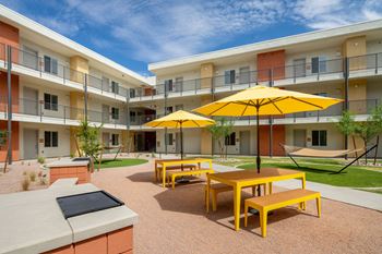 a courtyard with yellow tables and yellow umbrellas
