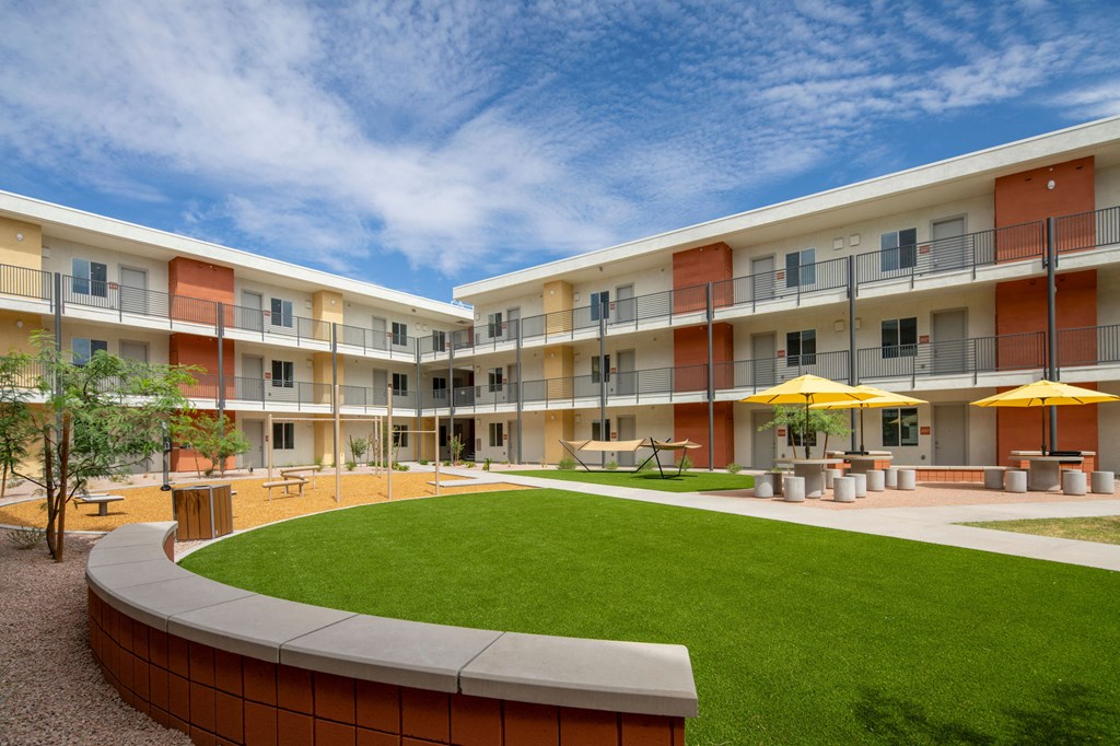 a courtyard with a grassy area and a lawn in front of an apartment building