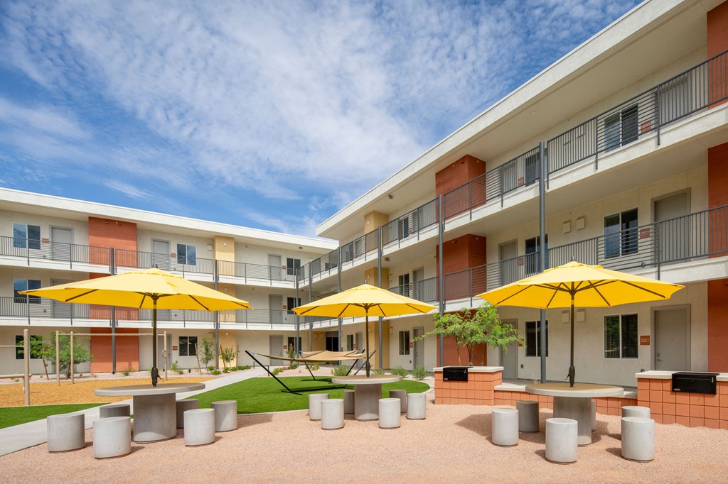 a courtyard with tables and chairs and yellow umbrellas