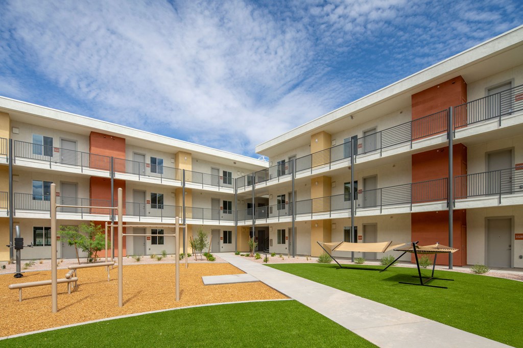 a courtyard with a picnic table and benches in front of an apartment building