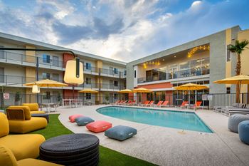 a swimming pool with lounge chairs and umbrellas in front of a building