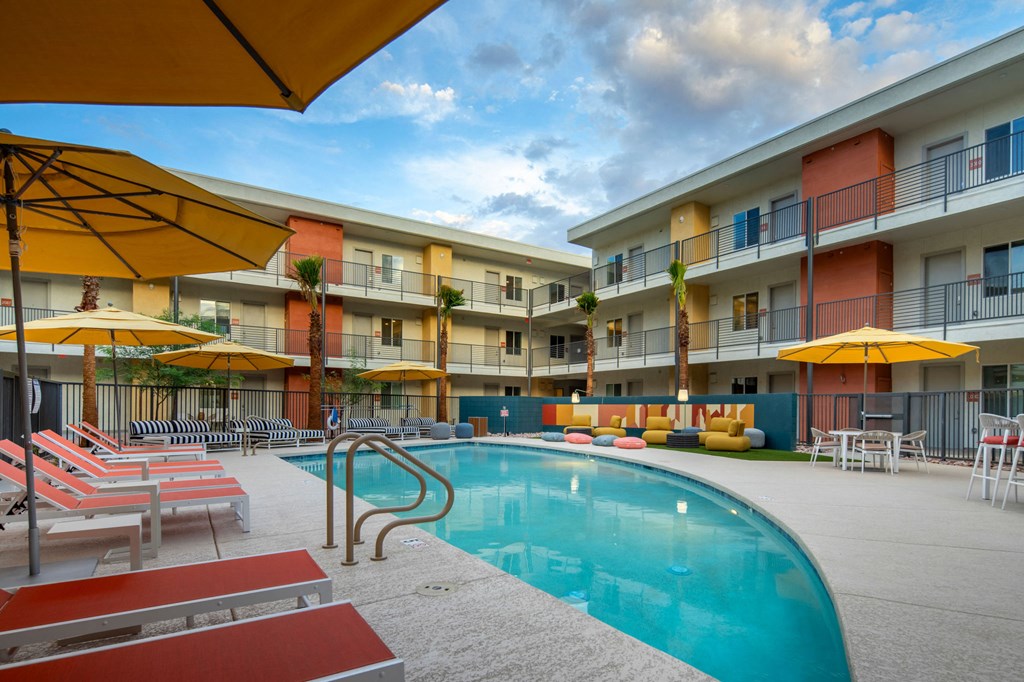 a swimming pool with yellow umbrellas and red and white lounge chairs