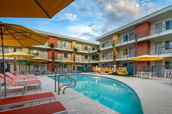 a swimming pool with yellow umbrellas and red and white lounge chairs