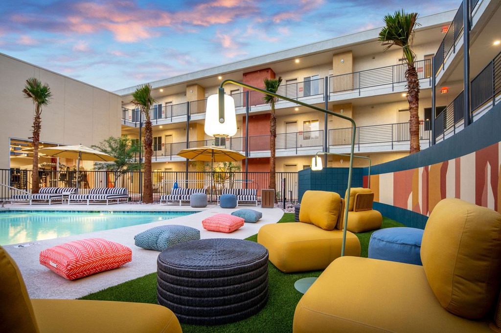 a courtyard with couches and pillows and a pool in front of a building