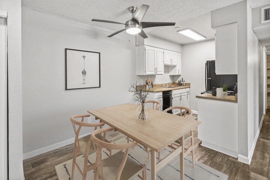 A dining area with a table and chairs and a kitchen in the background