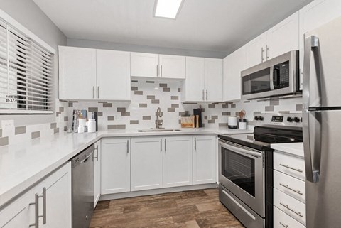 a kitchen with white cabinets and stainless steel appliances