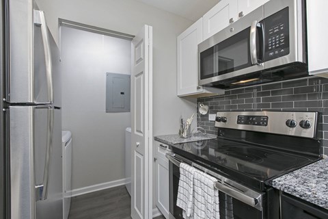 A kitchen with a black stove top oven and a silver microwave above it.