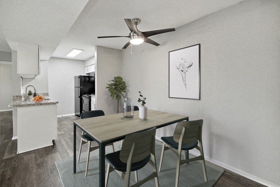 A dining area with a table and chairs and a kitchen in the background