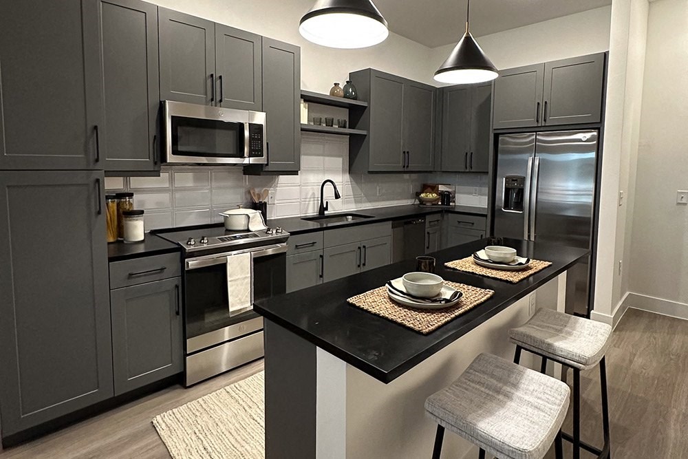 a kitchen with gray cabinets and stainless steel appliances