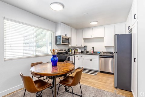 A kitchen with a table and chairs and a refrigerator.