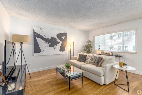 A living room with a white couch, a coffee table, and a large abstract painting on the wall.