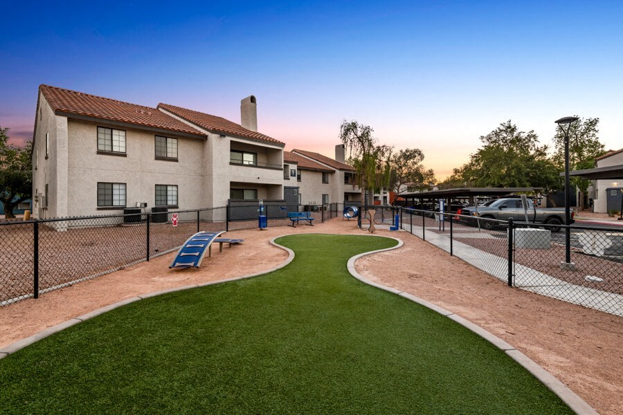 a fenced in dog park at sunset with apartments in the background at Lore South Mountain, Phoenix, 85044