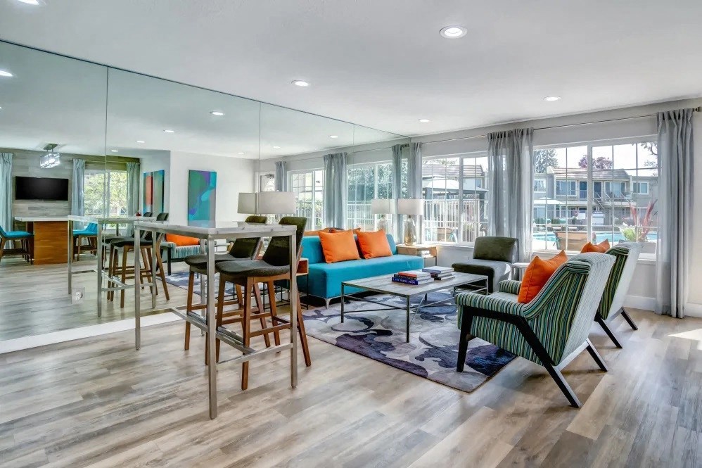A modern living room with a glass wall and a wooden floor.