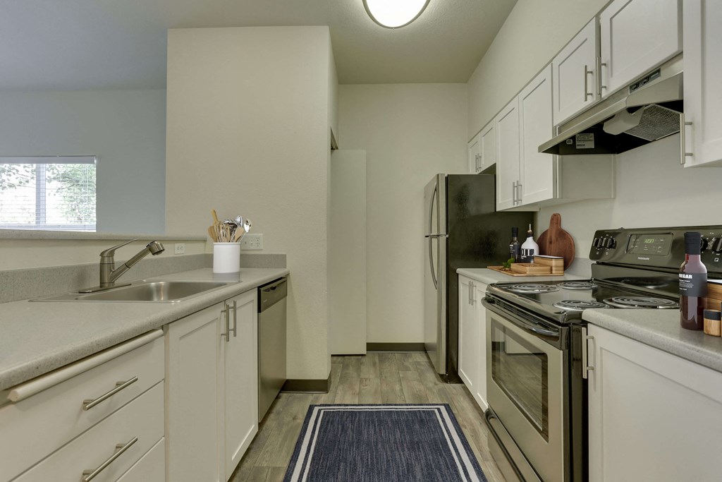 Model Kitchen with White Cabinets and Wood-Style Flooring at Landings at Morrison Apartments located in Gresham, OR.