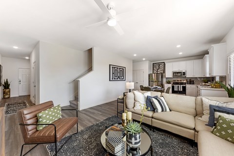 A living room with a brown leather chair and a beige couch with a glass coffee table in the middle.