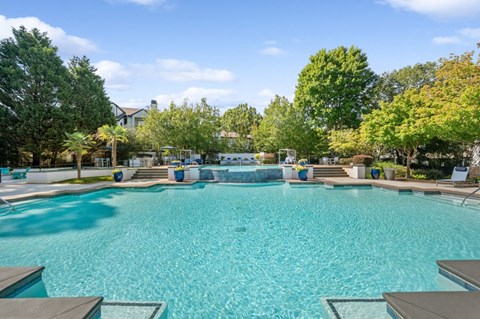 Lawrenceville, GA, Apartments with In-Unit Washer and Dryer - Parc at 980 - Resort Style Swimming Pool With Sparkling Water, Tiered Water Feature, Lounge Seating, And Lush Greenery Under Blue Sky.