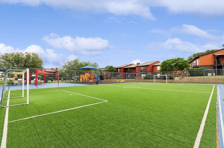 a grass soccer field with a playground in the background
