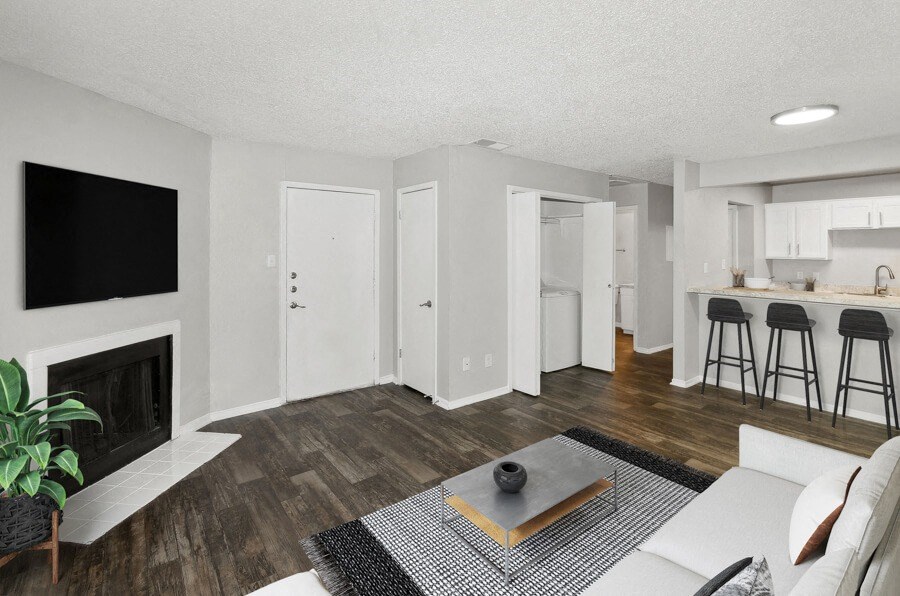 Model apartment living room with a fireplace and a kitchen