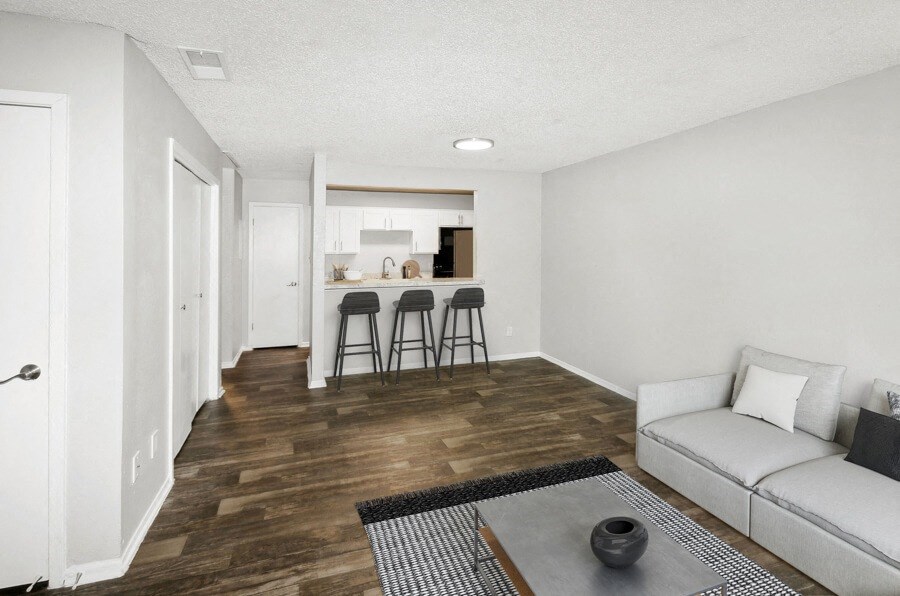 Model apartment living room with a couch and two bar stools