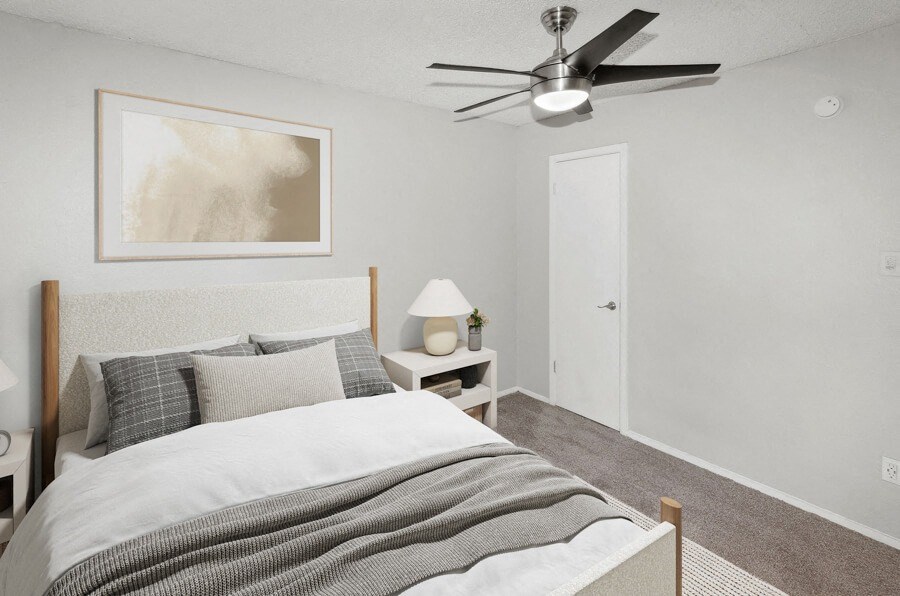 Model apartment bedroom with a bed and a ceiling fan