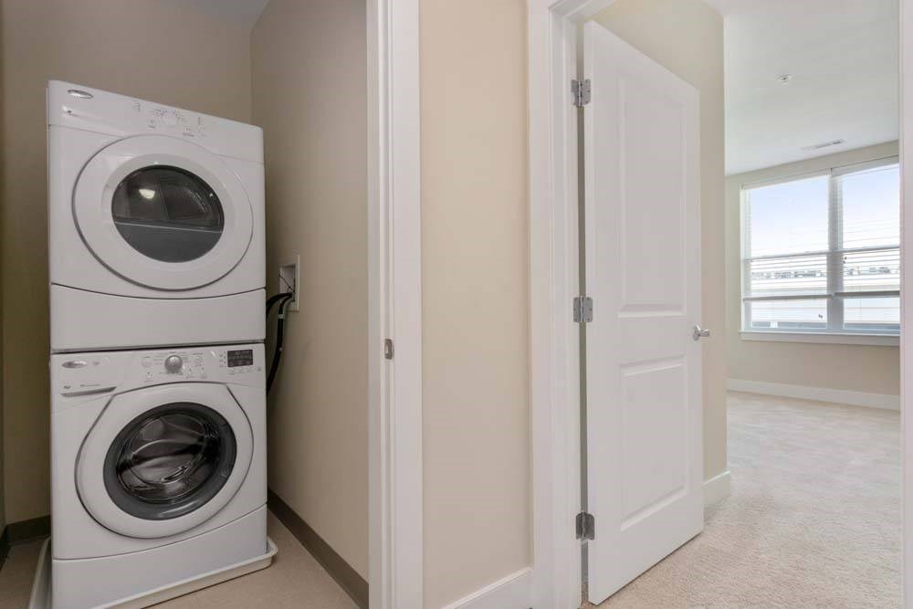 A white dryer and washer are stacked on top of each other in a laundry room.