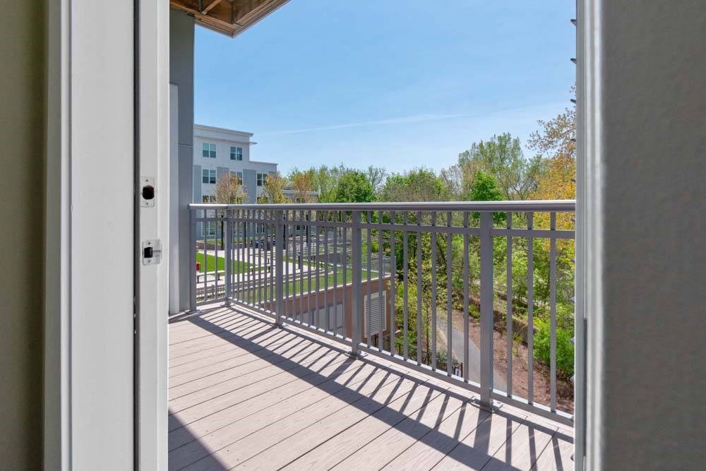 A balcony with a metal railing and a view of a building and trees.
