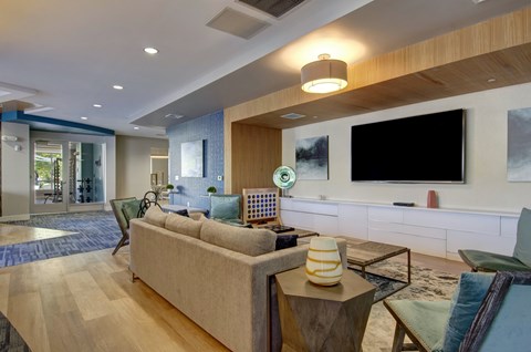 A modern living room with a large couch and a flat screen TV mounted on the wall.