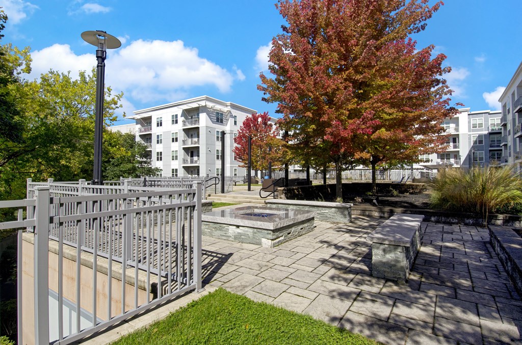A tree with red leaves stands next to a building.