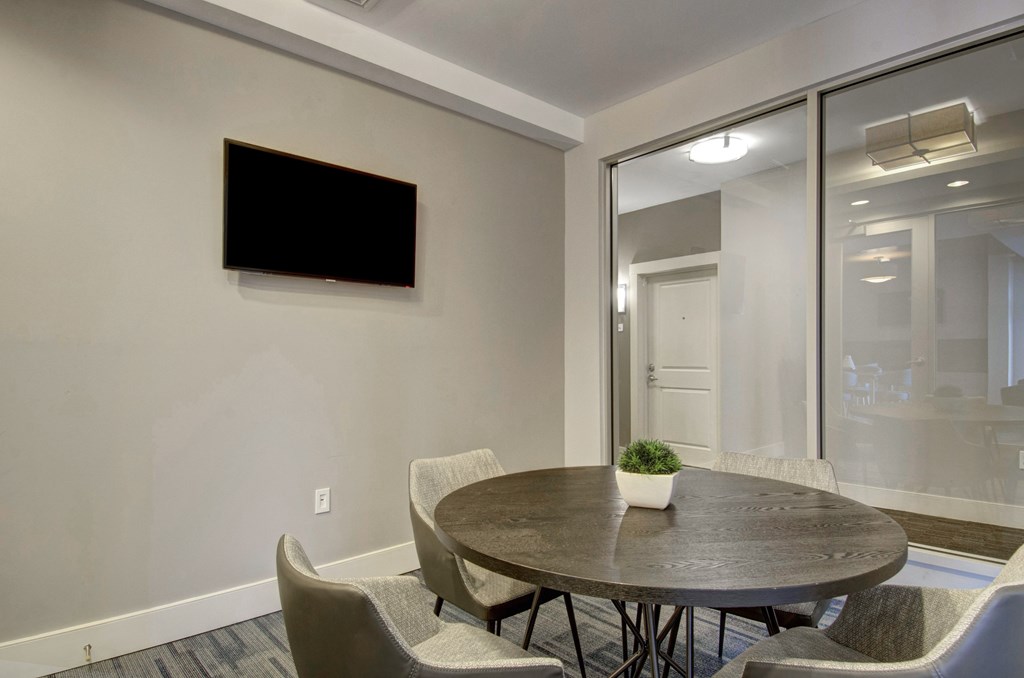 A conference room with a table, chairs, and a television on the wall.