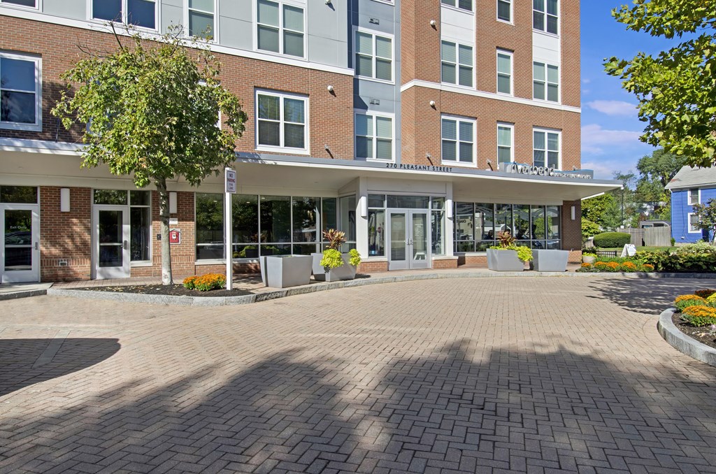 A large brick building with a glass entrance and a tree in front.