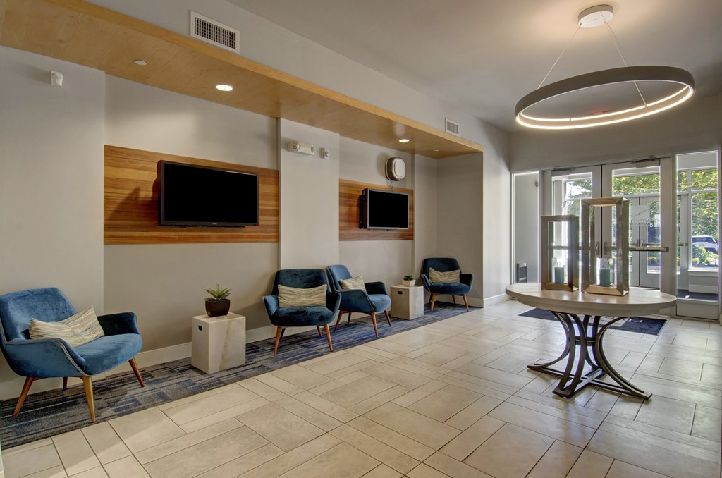 A spacious waiting area with blue chairs and a television mounted on the wall.