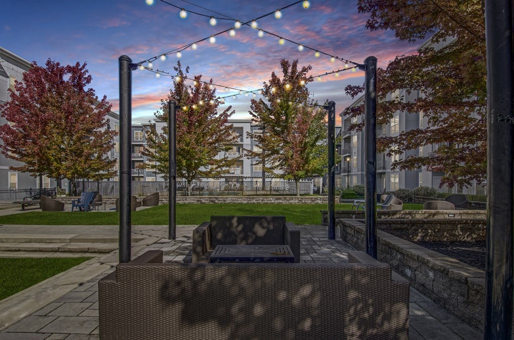 A park bench is in the foreground with a backdrop of trees and a building.