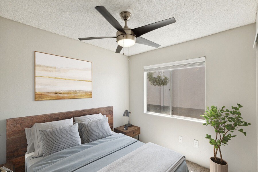 Model apartment bedroom with a bed and a ceiling fan