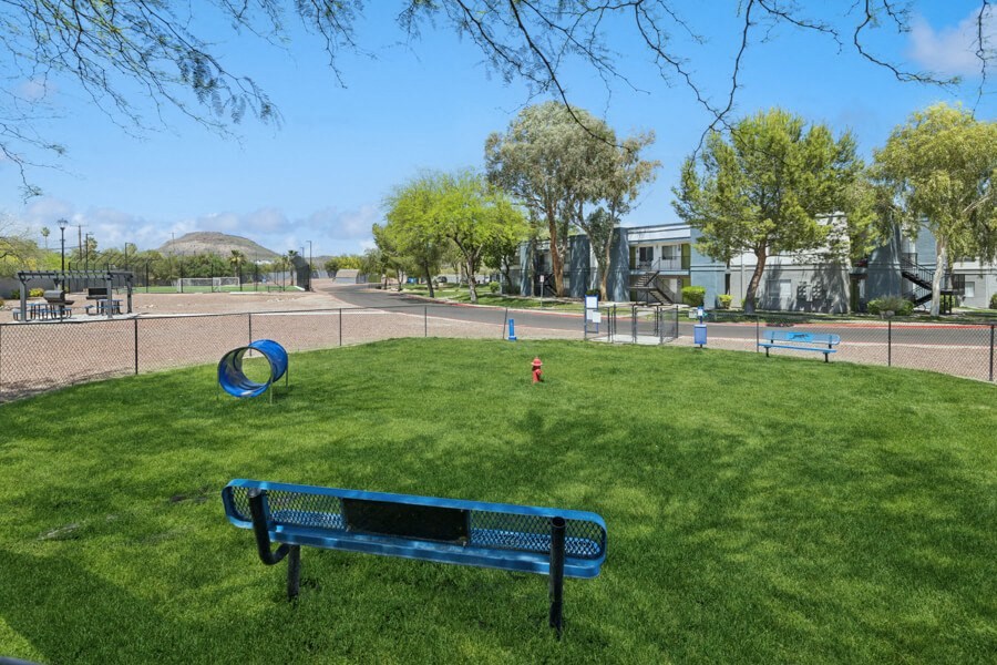 a park bench sitting in the grass near a playground