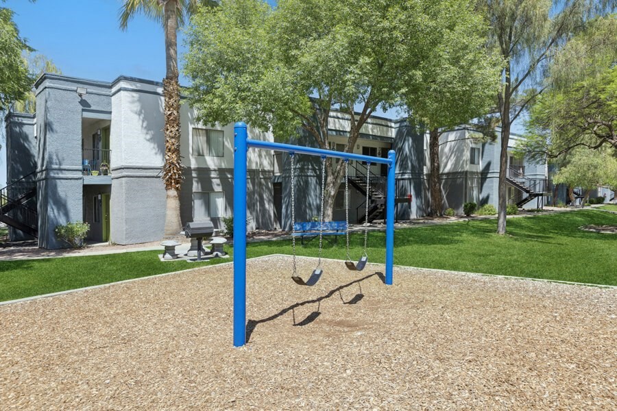 a swing set in a playground in front of apartments
